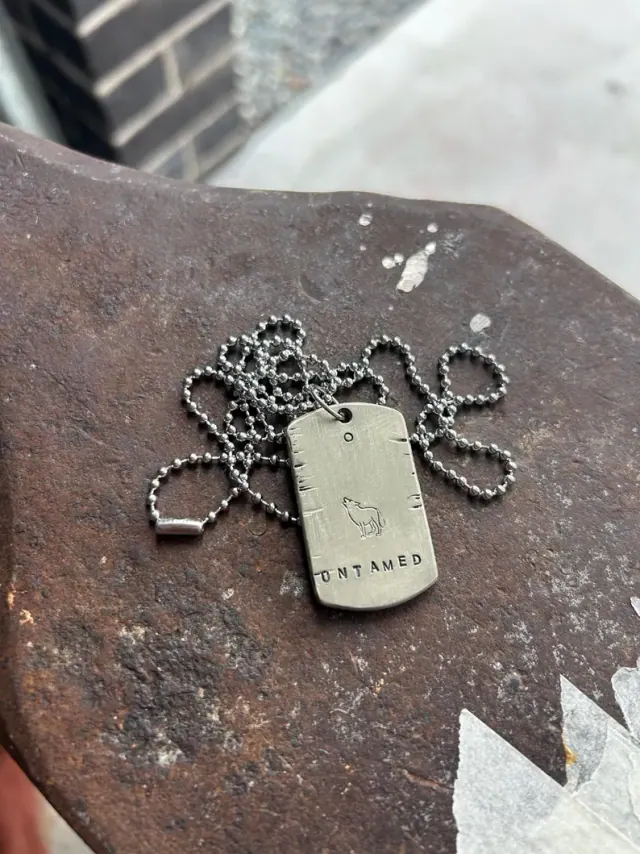 A hand-stamped Hammer & Heart piece resting on workshop tools