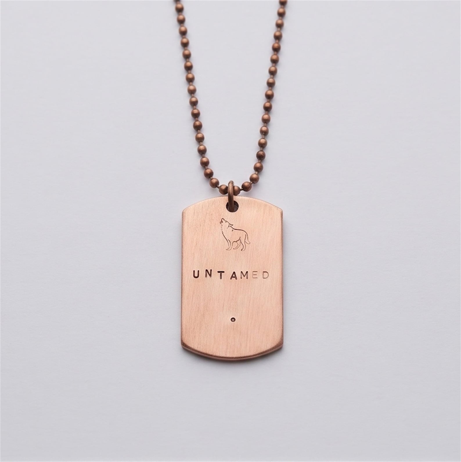 Hand-stamped copper UNTAMED dog tag necklace with wolf symbol